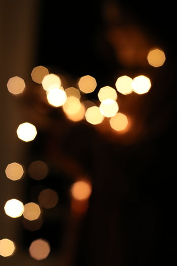 Golden bokeh lights creating an abstract and dreamy pattern on a dark background. HD phone wallpaper
