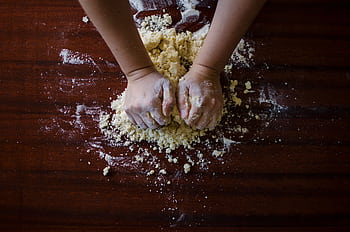 Close-up of hands kneading dough for baking on a wooden table, ideal for cooking themes. HD wallpaper