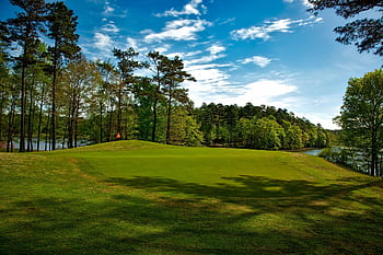 Beautiful golf course surrounded by trees and lake under a clear blue sky. HD wallpaper