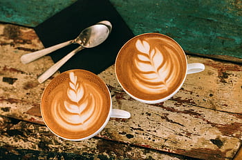 Café latte art on rustic table in Paris, capturing warm coffee moments. HD wallpaper