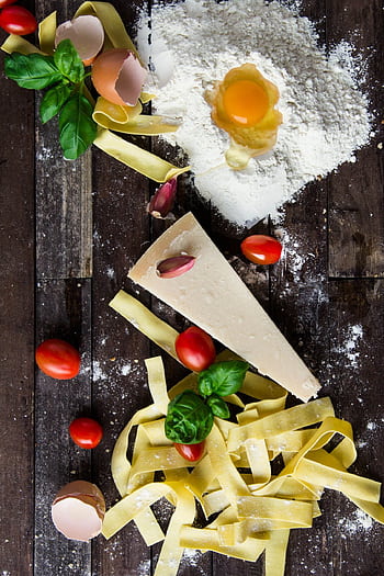 Top view of fresh pasta ingredients including flour, egg, parmesan, cherry tomatoes, and basil on a rustic wooden surface. HD phone wallpaper