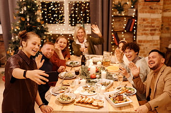 A joyful family gathering at a festive Christmas dinner table with decorations and cheerful faces. HD wallpaper