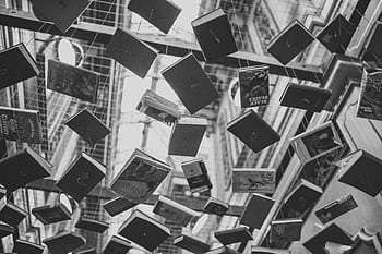 Artistic black and white of books suspended in mid-air inside a building. HD wallpaper