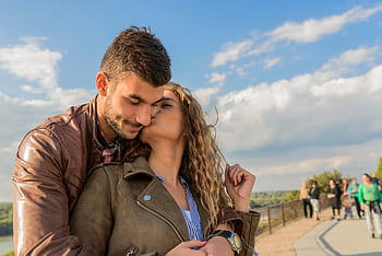 A loving couple embraces under a clear sky, showcasing romance and togetherness. HD wallpaper