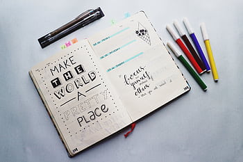 Open bullet journal with quotes and colorful markers for planning and creativity. HD wallpaper
