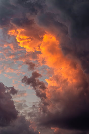Captivating cloud formation at sunset showcasing vibrant orange and dark clouds. HD phone wallpaper