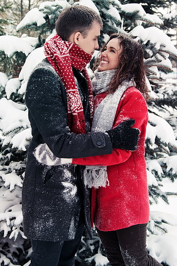 Couple enjoying a loving embrace in a snowy forest, exuding warmth and happiness. HD phone wallpaper
