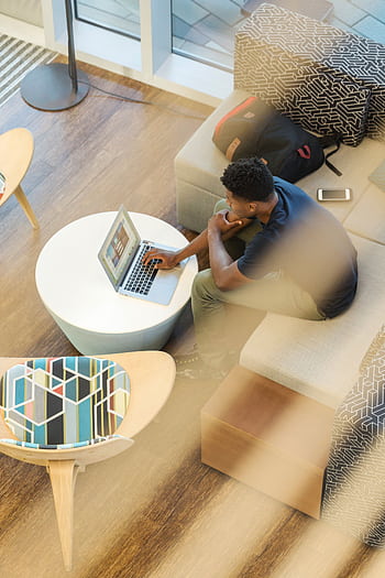 Young man working remotely on laptop in a stylish modern home interior setting. HD phone wallpaper