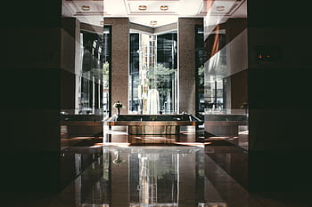 A sophisticated modern hotel lobby with glossy floors and natural light entering through large windows. HD wallpaper