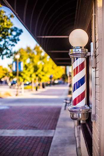 Classic barber pole on a vibrant city street under a sunny sky. HD phone wallpaper