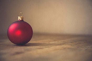A single red Christmas ornament with a gold cap on a rustic wooden surface, offering simple holiday elegance. HD wallpaper