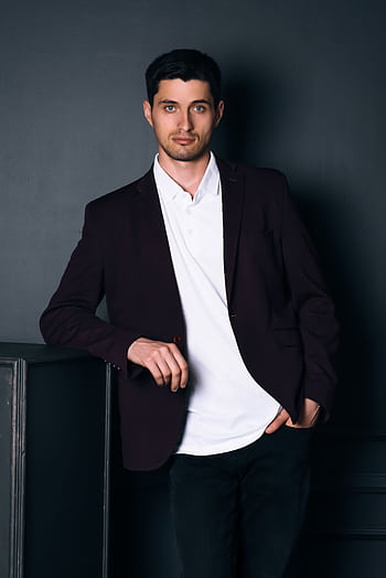 Confident man in a stylish suit posing indoors against a dark background. HD phone wallpaper