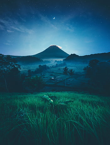 A breathtaking view of a moonlit mountain with vivid green fields, creating a serene and magical atmosphere. HD phone wallpaper