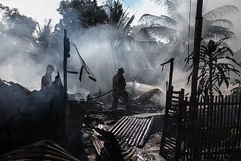 Brave firefighters battle a blaze amidst thick smoke in an outdoor setting. HD wallpaper