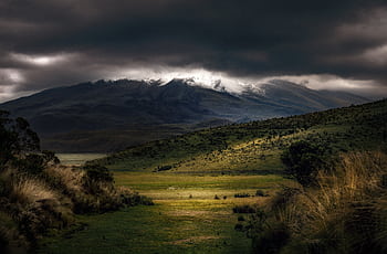 Stunning mountain landscape with dramatic dark clouds and green terrain. HD wallpaper