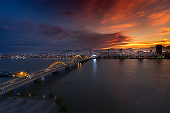 Beautiful sunset over the illuminated Dragon Bridge in Da Nang, Vietnam, highlighting the vibrant cityscape. HD wallpaper