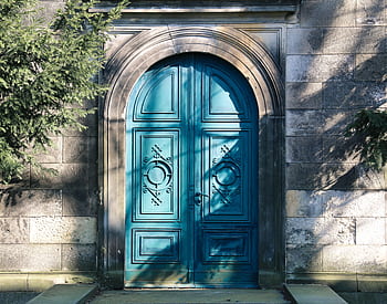 A vibrant blue arched door with gothic designs. Shadows of trees add depth. HD wallpaper