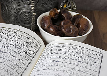 An open Quran with a bowl of dates, symbolizing Ramadan and Islamic traditions. HD wallpaper