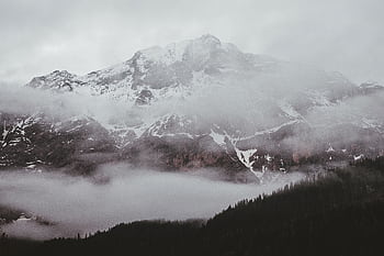 A breathtaking view of a snowy mountain peak shrouded in fog, perfect for nature lovers. HD wallpaper
