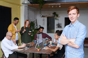 Young professional leading a diverse team in a contemporary office setting. HD wallpaper