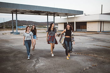 A group of young women laughing and walking together outdoors, enjoying the day. HD wallpaper