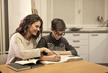 Brother and sister studying together at home, focusing on homework and learning. HD wallpaper