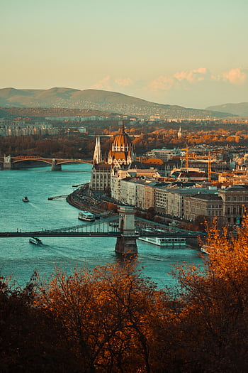 A breathtaking view of Budapest's cityscape featuring iconic bridges and the Danube River at sunset. HD phone wallpaper