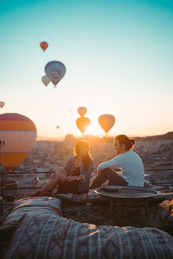 A couple enjoys a romantic sunrise with hot air balloons in Cappadocia, Turkey. HD phone wallpaper