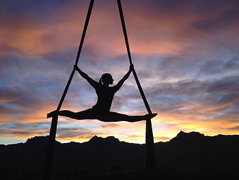 Silhouette of a woman practicing aerial yoga against a vibrant sunset sky in Las Vegas. HD wallpaper