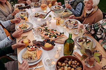 A warm outdoor family dinner with diverse dishes and joyful conversation, perfect for festive gatherings. HD wallpaper