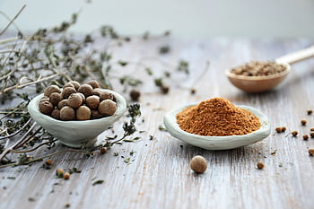 An artistic display of whole and ground spices in ceramic bowls on a rustic wooden surface, emphasizing culinary tradition. HD wallpaper