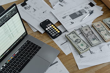 A desk with financial documents, currency, a laptop, and calculator. HD wallpaper