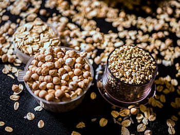 Close-up of assorted raw grains and seeds in cups on a dark background, showcasing variety and texture. HD wallpaper