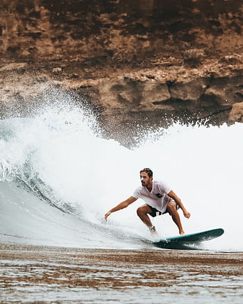 A surfer expertly riding a large wave on a sunny day at the beach. HD phone wallpaper