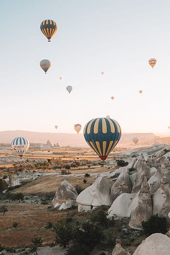 Stunning view of hot air balloons in the sky over Cappadocia's unique rock formations at sunrise. HD phone wallpaper
