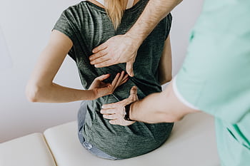 A chiropractor examining a patient's back to alleviate pain and discomfort. HD wallpaper