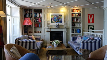 Stylish living room with modern decor, striped couches, and a cozy fireplace. HD wallpaper
