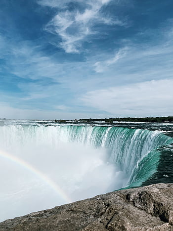 Breathtaking capture of Niagara Falls showcasing a vivid rainbow and clear blue sky. HD phone wallpaper