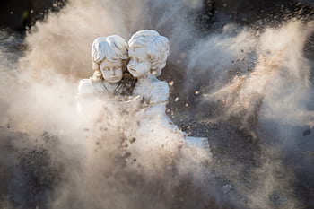Intricate stone statues engulfed in a dynamic dust explosion, creating a dramatic artistic effect. HD wallpaper