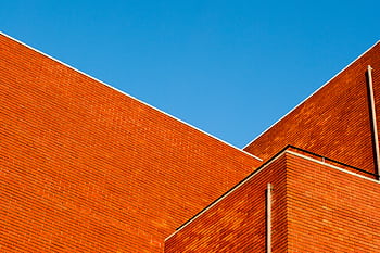 Abstract view of a modern brick building exterior against a clear blue sky. HD wallpaper