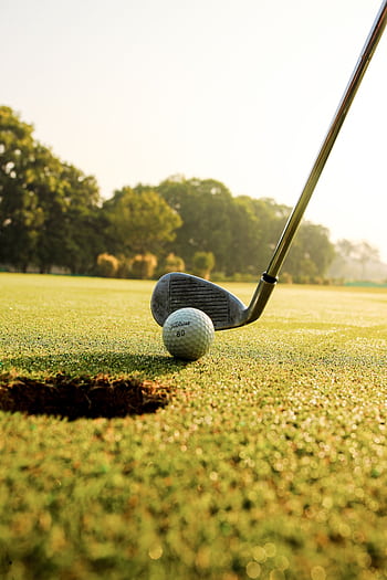 Golf club and ball near hole on a lush green course in bright daylight. HD phone wallpaper