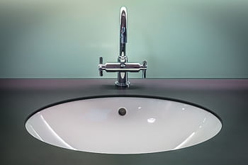 A sleek modern bathroom sink with a shiny stainless steel faucet on a dark vanity. HD wallpaper