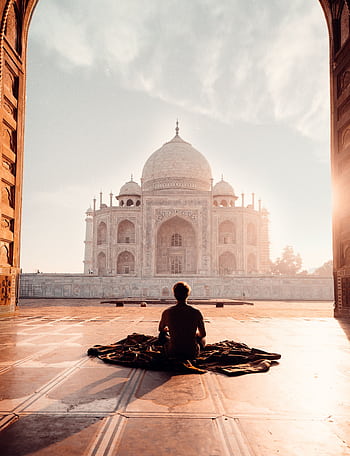 A person meditates at sunrise facing the iconic Taj Mahal, capturing serenity and majesty. HD phone wallpaper