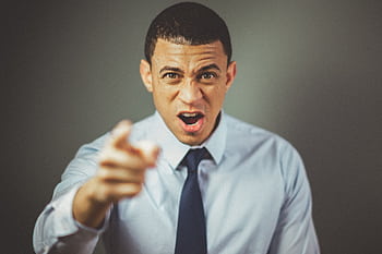Close-up of an angry businessman in a tie expressing frustration and pointing. HD wallpaper