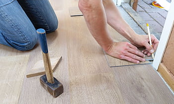 A craftsman carefully measures and marks wooden floor panels for precise installation. HD wallpaper