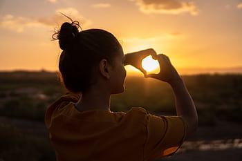 A silhouette of a young woman forming a heart shape at sunset in Kelâat M'Gouna, Morocco. HD wallpaper