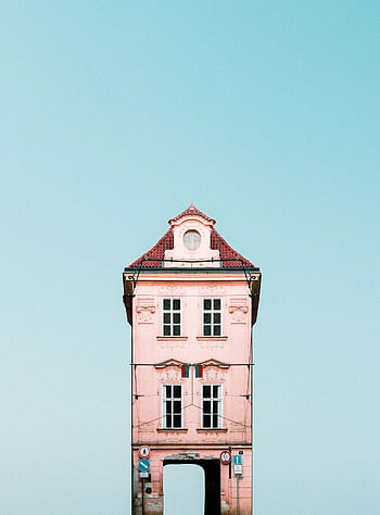 A quaint pink house with red roof against a clear blue sky, showcasing architectural beauty. HD phone wallpaper