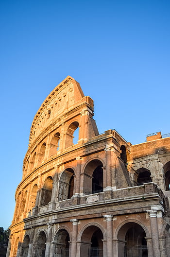 Capture of the iconic Colosseum in Rome with clear blue skies, highlighting its historic architecture. HD phone wallpaper