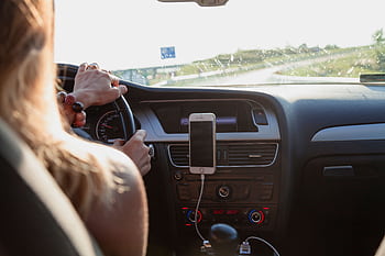 View from behind a woman driving a car on a sunny day with a mounted on the dashboard. HD wallpaper