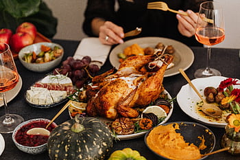 A festive Thanksgiving dinner spread featuring a golden roasted turkey, vegetables, and wine, perfect for holiday dining. HD wallpaper